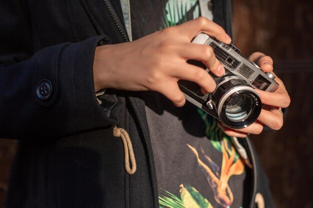Fotografo ragazza con una vecchia macchina fotografica nelle sue mani. Fotografo ragazza alla moda alla moda nella via della città