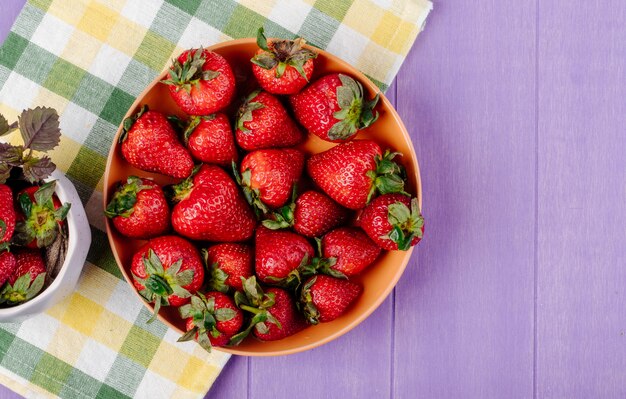 Fragola fresca di vista superiore su un piatto su fondo porpora