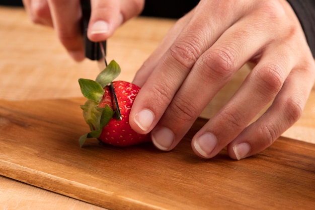 Fragole di taglio della persona del primo piano