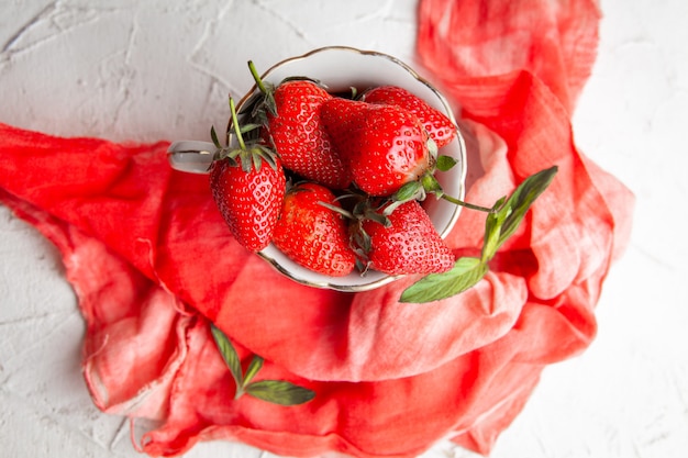 Fragole di vista superiore in tazza di caffè sul panno rosso su fondo bianco. orizzontale