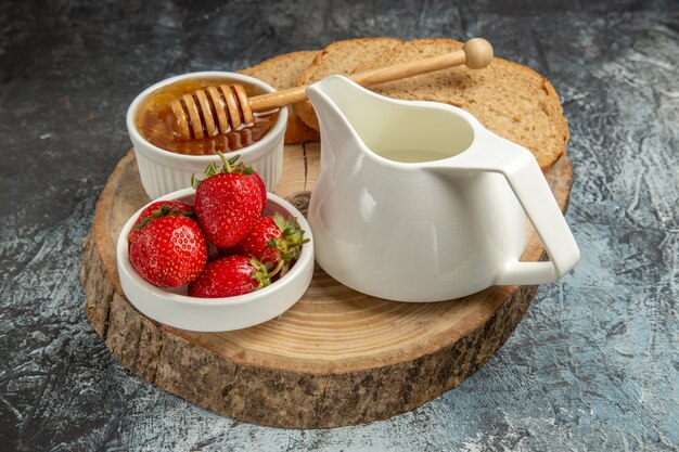 Fragole fresche di vista frontale con miele sulla gelatina dolce della frutta di superficie scura