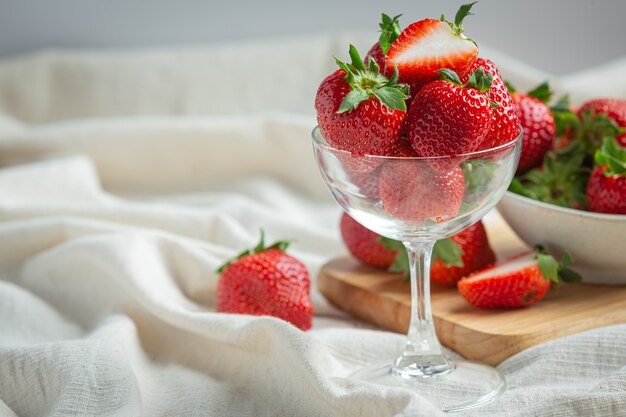 Fragole fresche in vetro sulla tavola di legno