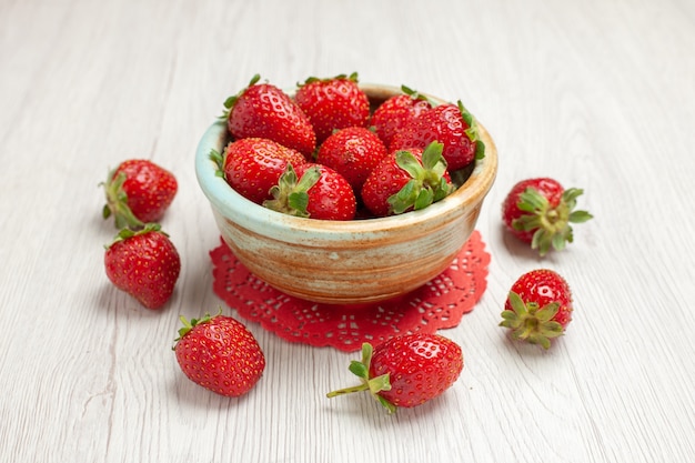 Fragole rosse di vista frontale sulla bacca della frutta di colore rosso dello scrittorio bianco fresca