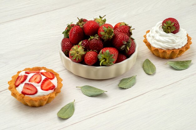 fragole rosse fresche bacche morbide e deliziose all'interno del piatto con torte sulla scrivania leggera