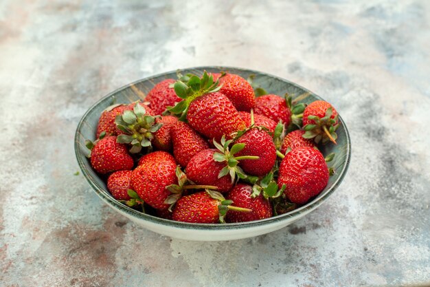 Fragole rosse fresche di vista frontale all'interno del piatto su una bacca matura selvaggia di colore dell'albero della pianta da frutto del fondo bianco