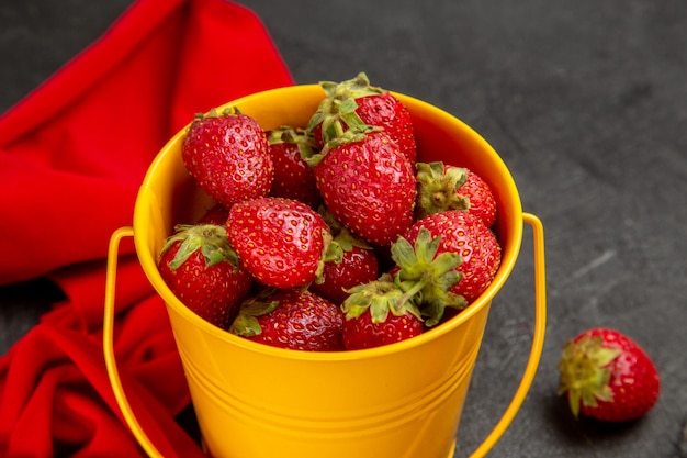 Fragole rosse fresche di vista frontale all'interno del piccolo canestro sui precedenti scuri