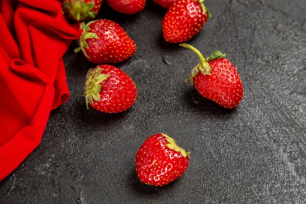 Fragole rosse fresche di vista frontale sui precedenti scuri