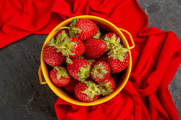 Fragole rosse fresche di vista superiore all'interno del piccolo canestro sulla bacca della frutta della tavola scura