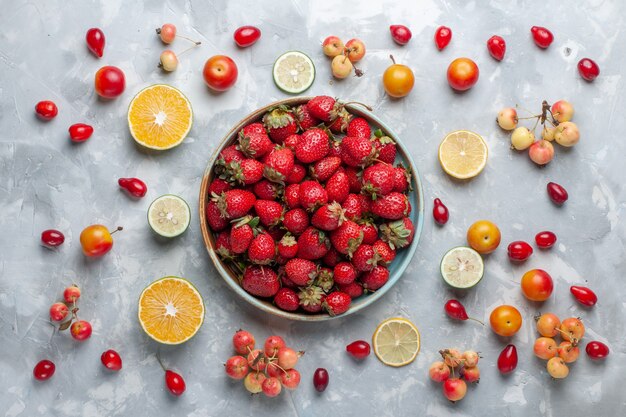Fragole rosse fresche di vista superiore con il limone e le ciliege sulla vitamina mellow della bacca della frutta bianca dello scrittorio