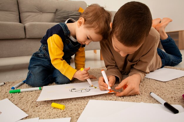 Fratelli a figura intera che disegnano a casa