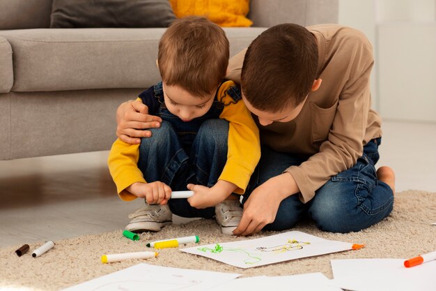 Fratelli a figura intera che disegnano a casa