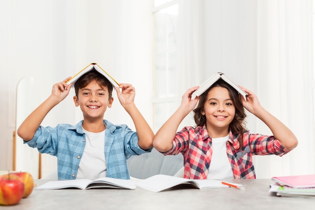 Fratelli germani a casa con i libri in cima alla testa