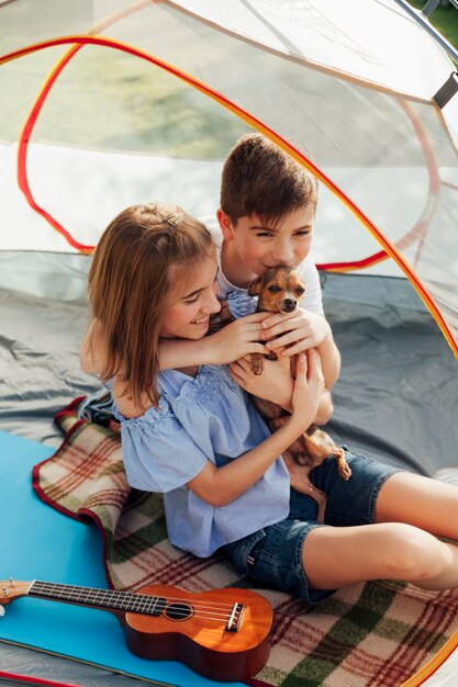 Fratello e sorella che amano il loro animale domestico seduto in tenda