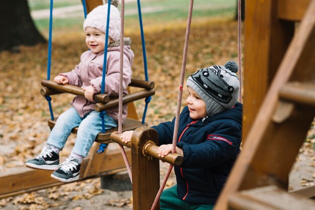 Fratello e sorella del bambino sul campo da giuoco di autunno