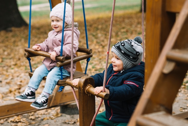 Fratello e sorella del bambino sul campo da giuoco di autunno