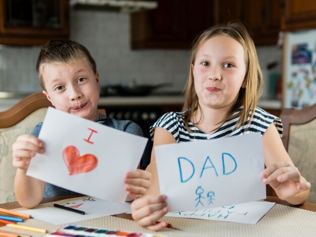 Fratello e sorella svegli che disegnano per la festa del papà