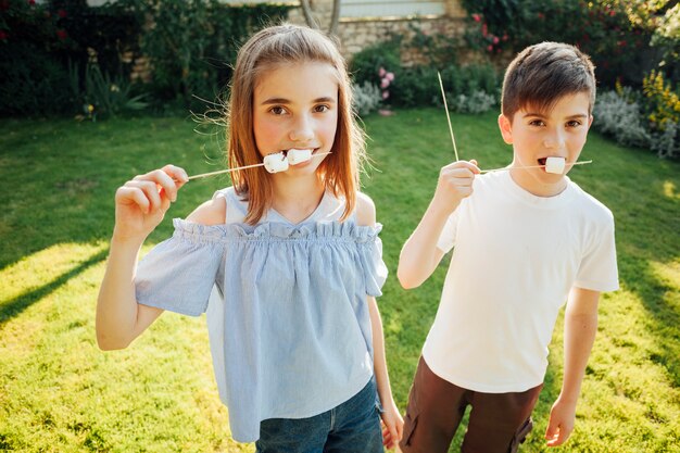 Fratello germano che mangia caramella gommosa e molle e che guarda l&#39;obbiettivo