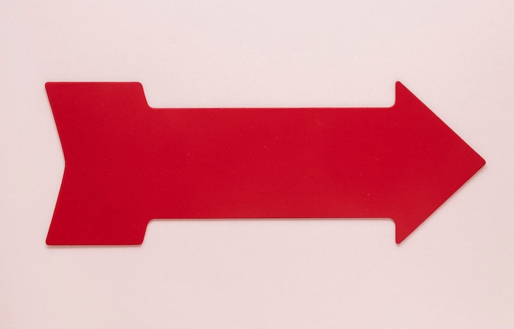 Foto gratuito freccia rossa piana di disposizione su fondo rosa