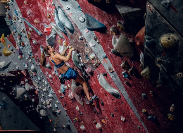 Free climber boulder femminile al chiuso. Vista posteriore.