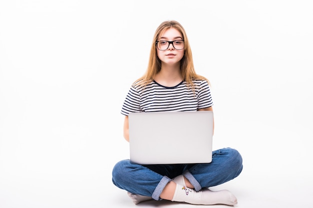 Freelance o lavoro a casa laptop. La bella donna in casuale si siede sul pavimento e lavora con il computer portatile con le gambe attraversate