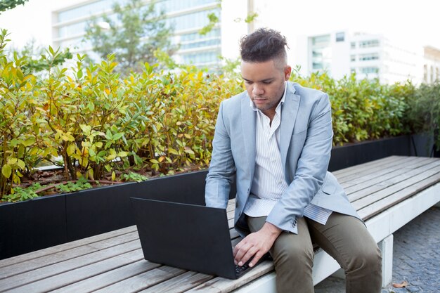 Freelancer serio che lavora al computer portatile all&#39;aperto