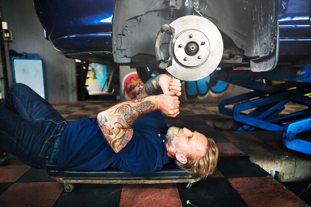 Freno a disco reparing dell&#39;automobile di riparazione dell&#39;uomo caucasico del meccanico nel garage