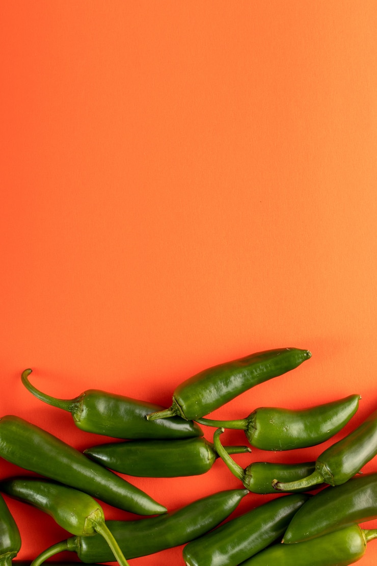 Foto gratuito fresco piccante del peperone verde su fondo arancio