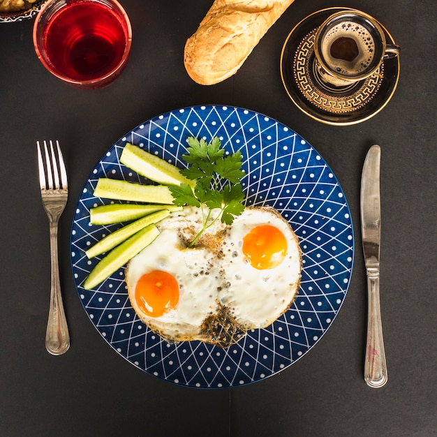 Frittata fritta con fette di cetriolo e coriandolo sul piatto blu