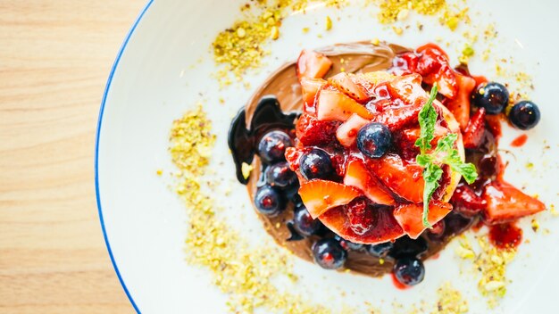 Frittelle con frutta mista di bacche in piatto bianco