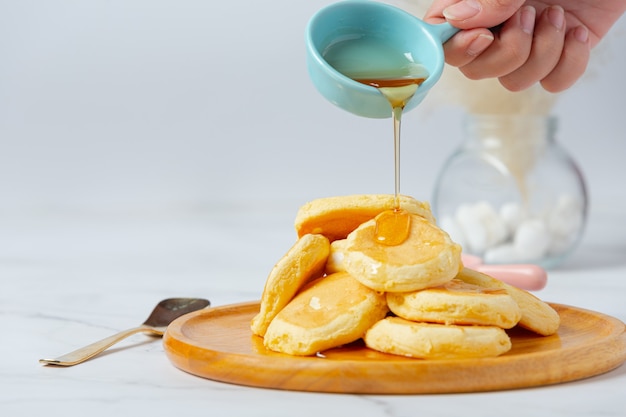 Frittelle con sciroppo d'acero nel piatto su priorità bassa bianca