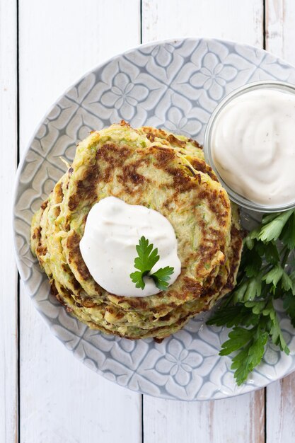 Frittelle di zucchine con salsa di yogurt su tavola di legno