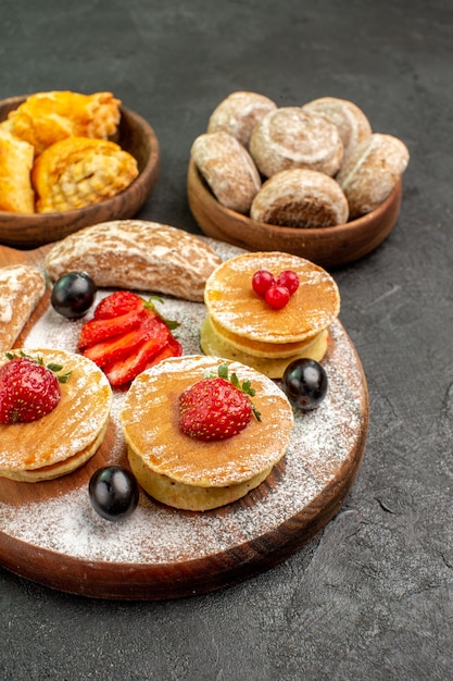 Frittelle gustose vista frontale con frutta e torte dolci sul dessert torta dolce superficie scura