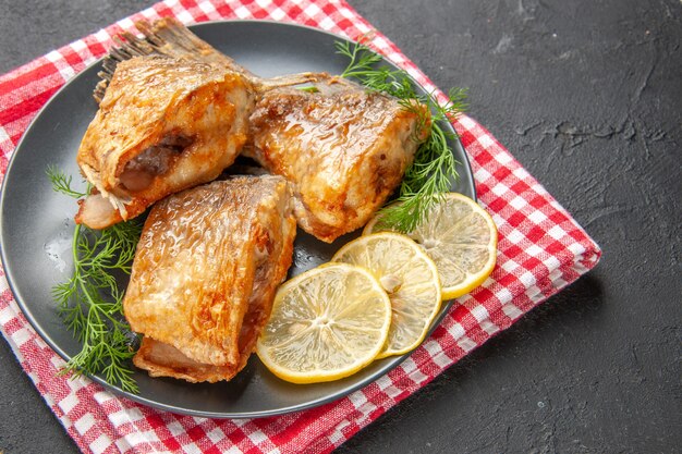 Frittura di pesce vista dal basso con fette di limone su piatto su tovagliolo su sfondo nero