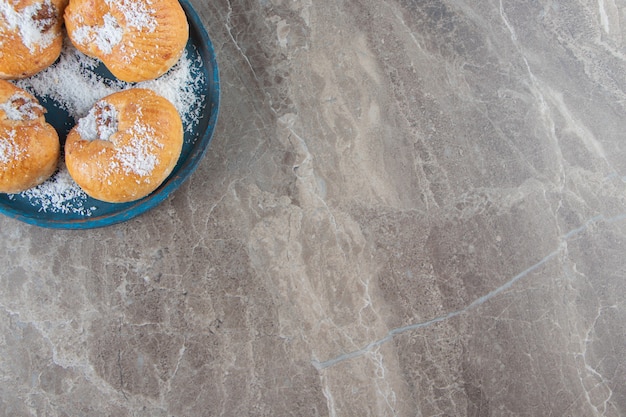 Frollini al miele con scaglie di cocco su un piatto di legno su marmo.