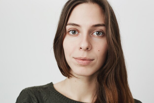 Fronte attraente della giovane donna del primo piano che osserva macchina fotografica