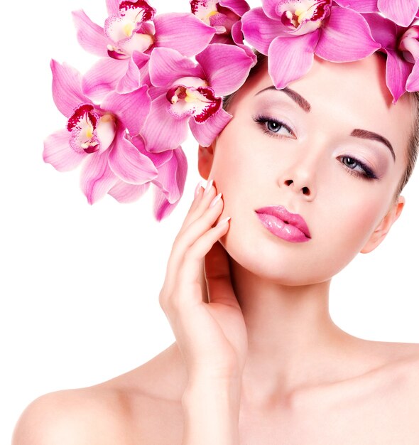 Fronte del primo piano di una giovane donna bellissima con un trucco occhi viola e labbra. Bella ragazza adulta con fiore vicino al viso. - isolato su sfondo bianco