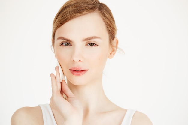 Fronte di pulizia della bella ragazza bionda naturale con sorridere della spugna di cotone. Cosmetologia e spa.