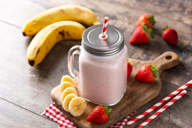 Frullato di banana e fragola fresca in barattolo sulla tavola di legno