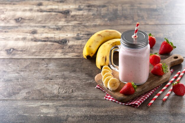 Frullato di banana e fragola fresca in barattolo sulla tavola di legno