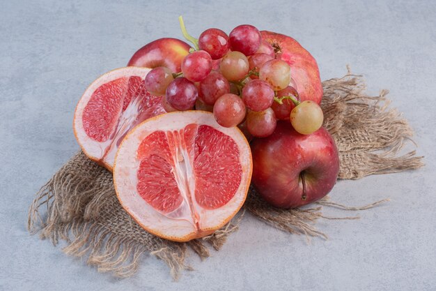 Frutta biologica fresca. Mela, uva e mandarini su sfondo grigio.