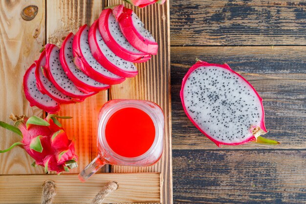 Frutta del drago con succo in un vassoio sulla tavola di legno, disposizione piana.