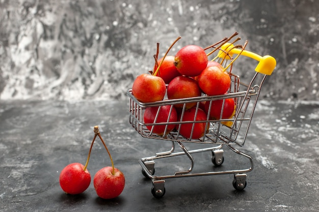 Frutta fresca della ciliegia rossa in carrello su fondo grigio