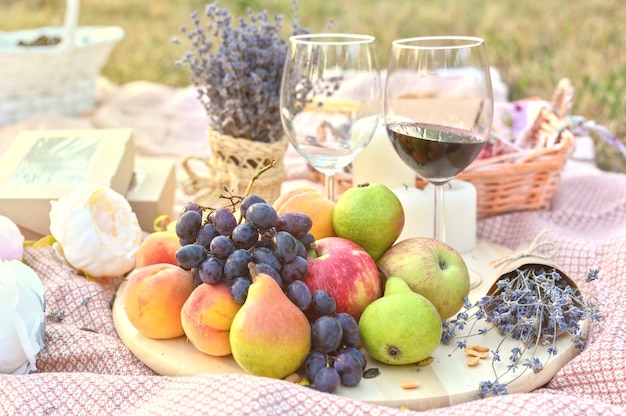 Frutta fresca e picnic in vetro di vino all'aperto
