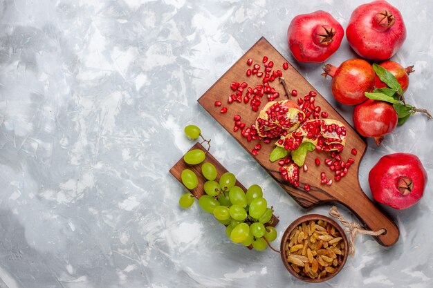 Frutta fresca e succosa del melograno rosso di vista superiore con l'uva sullo scrittorio bianco