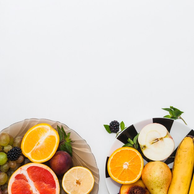 Frutta fresca in buona salute nella ciotola e piatti su fondo bianco