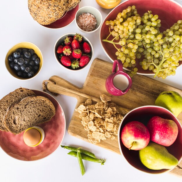 Frutta fresca, pane e latte su sfondo bianco