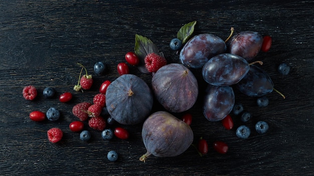 Frutta matura e bacche con erbe su fondo di legno nero