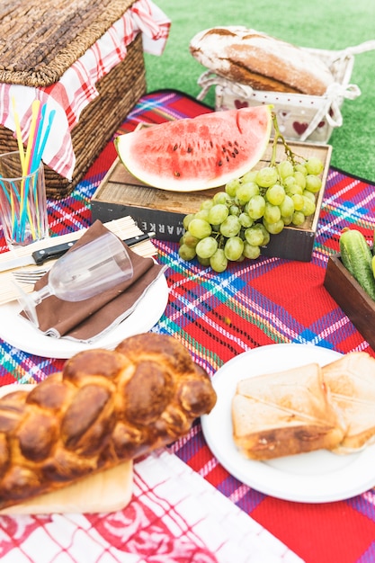 Frutta; panini e pagnotta di pane intrecciata al forno sulla coperta