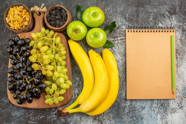 frutta uva frutta secca banane tre mele quaderno crema e matita verde