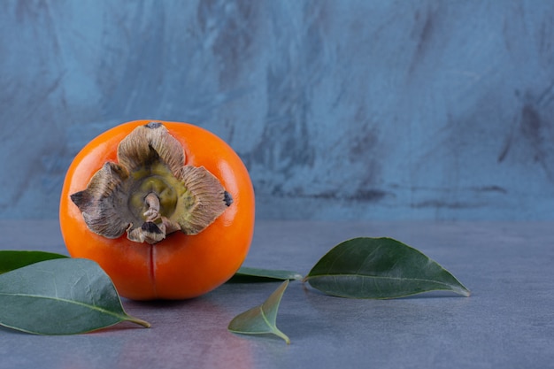 Frutti e foglie di cachi, sulla superficie scura